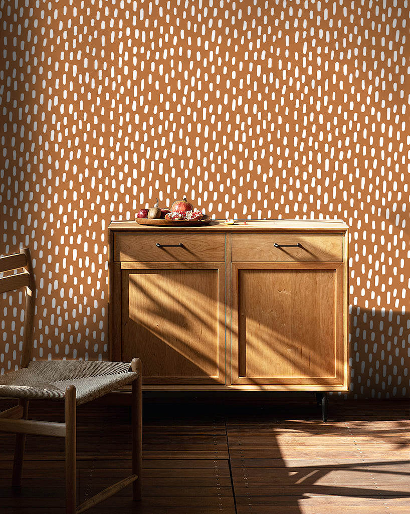 HaokHome terracotta speckle peel and stick wallpaper, tiny off-white dash pattern on warm clay background, accent wall beside wooden sideboard cabinet